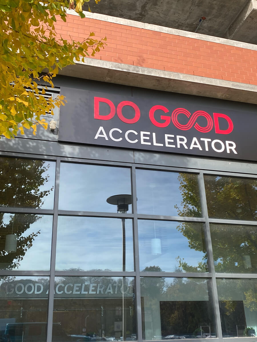 Exterior of the Do Good Accelerator building with its red and black sign above large reflective windows