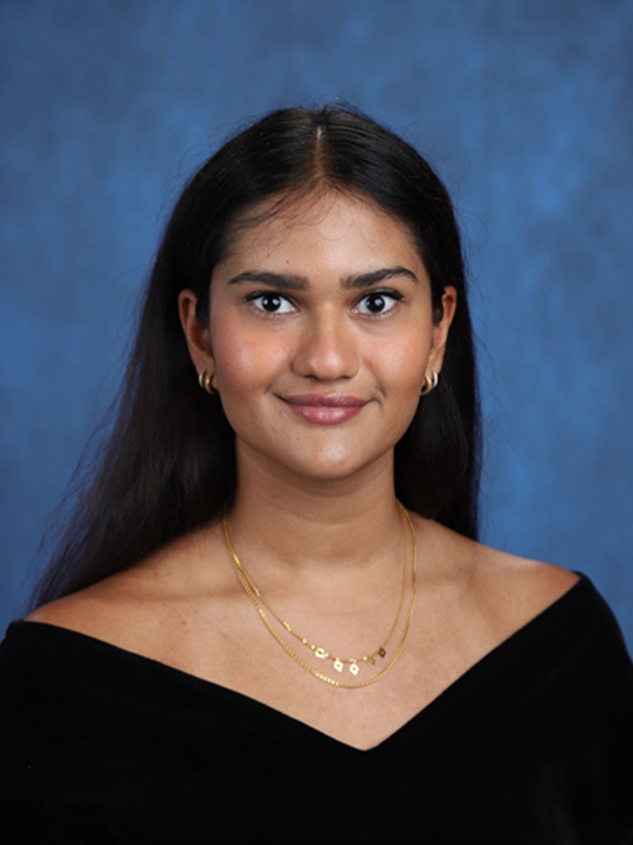 Simran's headshot is her with a black graduation cover and a blue background