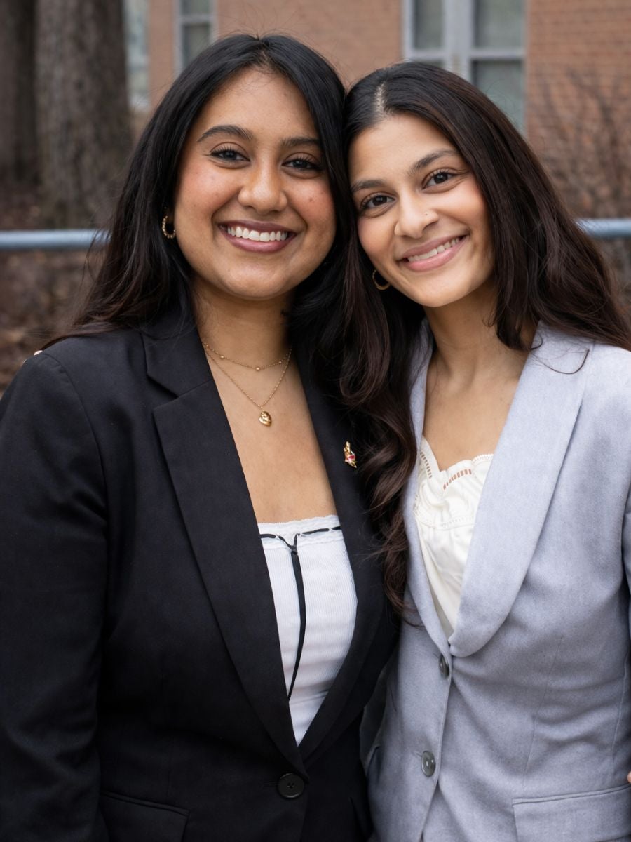 Two students pose for a photo smiling and wearing professional attire.