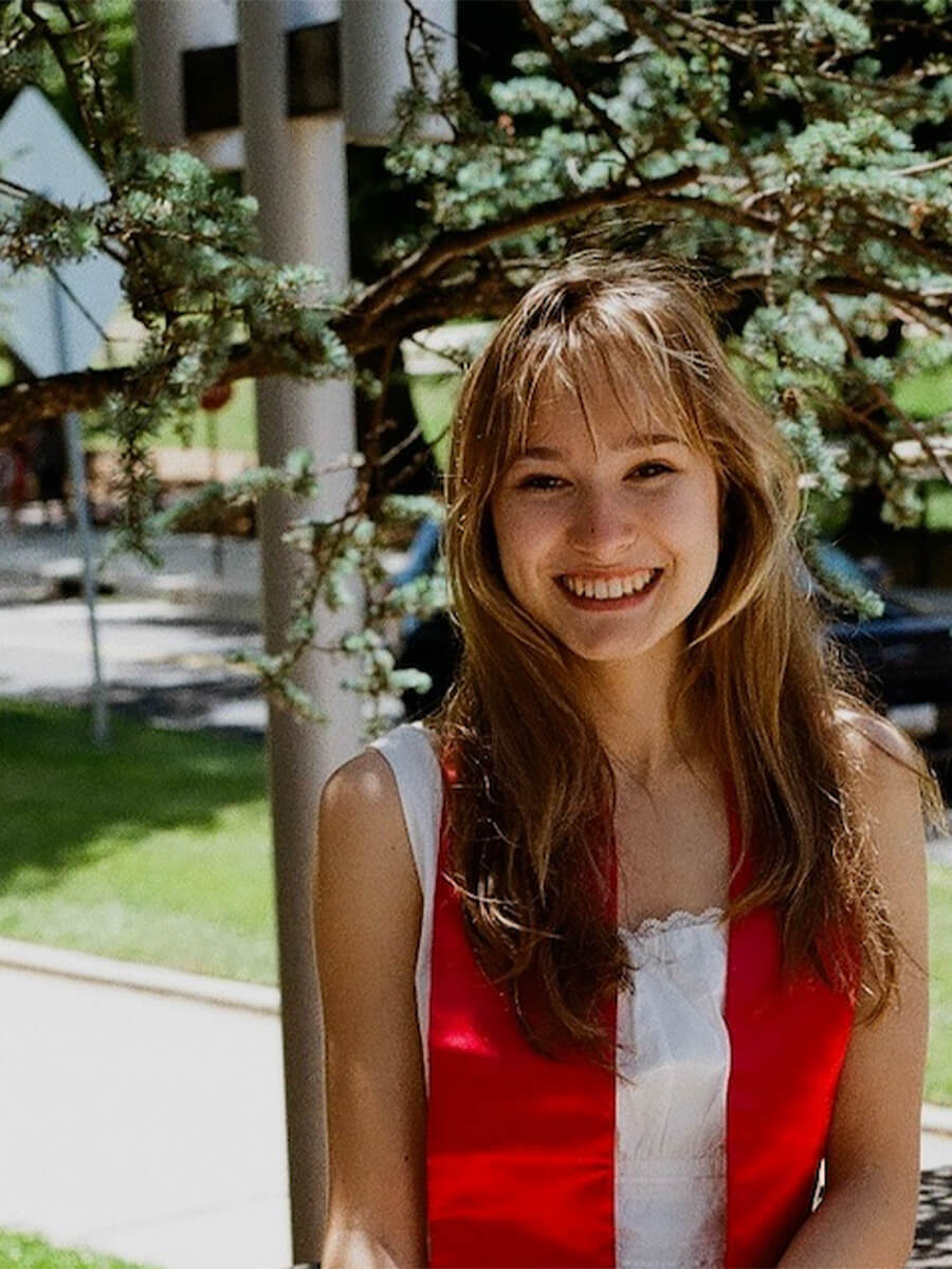 Woman posing for a photo in a white top and red stoll 