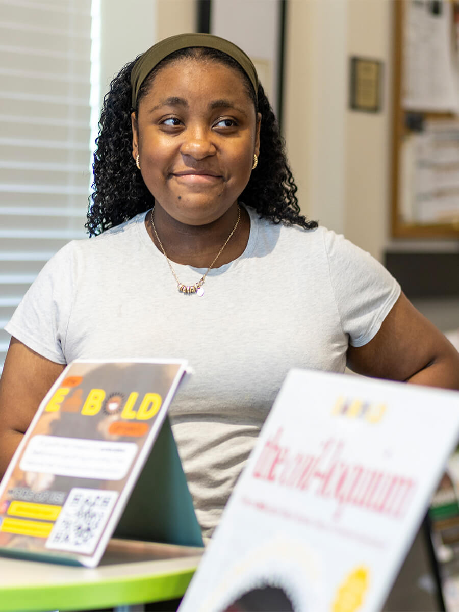 Photo of student in front of two books smiling 