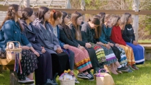Image of First Nation women in colorful skirts sitting outdoors