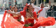 Woman in red traditional Hispanic dress dancing in street parade