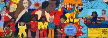 Mural on a brick wall depicting difference scenes of Hispanic people