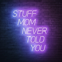 Stuff Mom Never Told You in neon purple and pink lettering on a black background