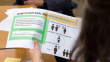 image of a person reading a pamphlet that says "What is our goal and how do we reach it?"