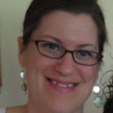 a white woman with glasses and silver earrings