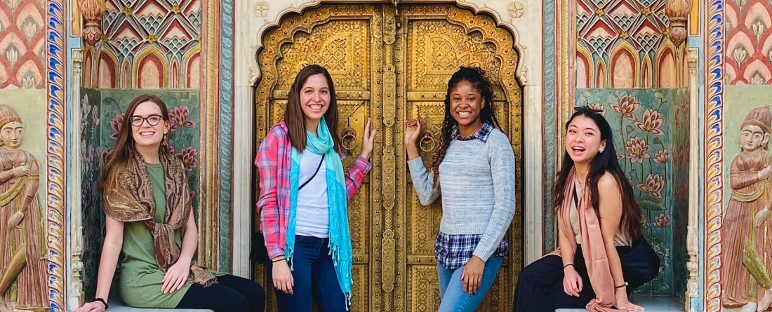four students in front of intricate door in india