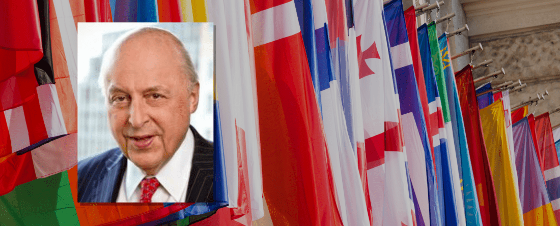 Image of Negroponte in front of wall of flags 