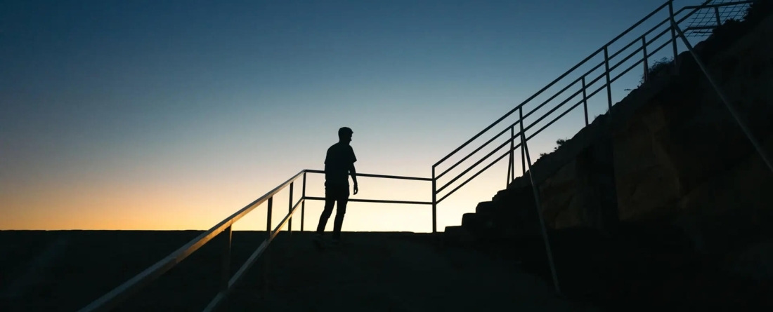 Silouette of person walking up stairs at dusk