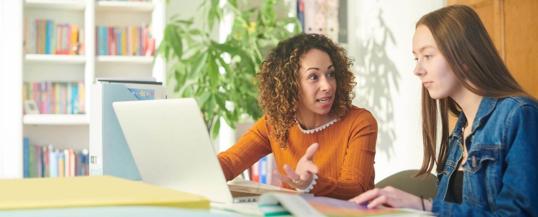 2 women sitting at a computer talking