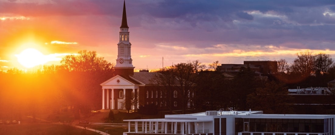 The sun is setting with the campus chapel and Thurgood Marshall Hall in the background. 