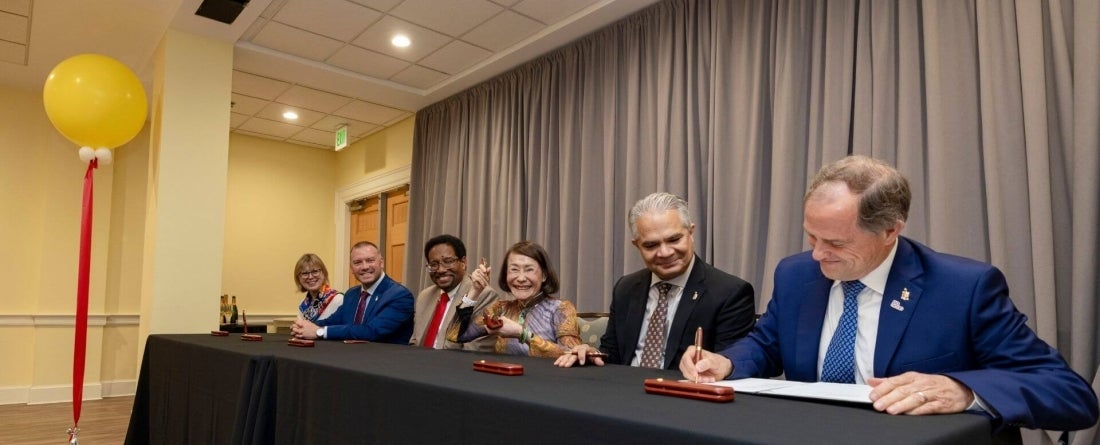 people sitting at a table with black tablecloth against a gray curtain
