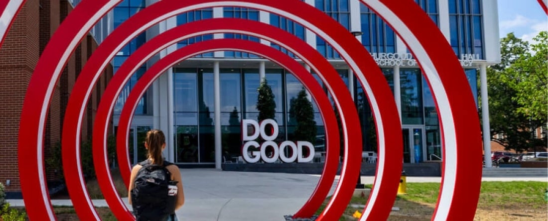 A student walks through the red do good rings outside Thurgood Marshall Hall.