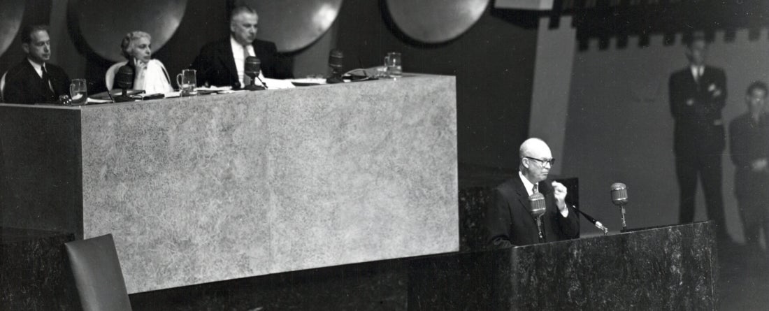 Historical black and white photo of a speaker and panelists