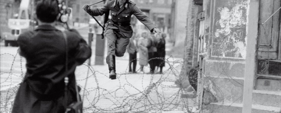 Photograper snapping photo of military man jumping over barbed wire