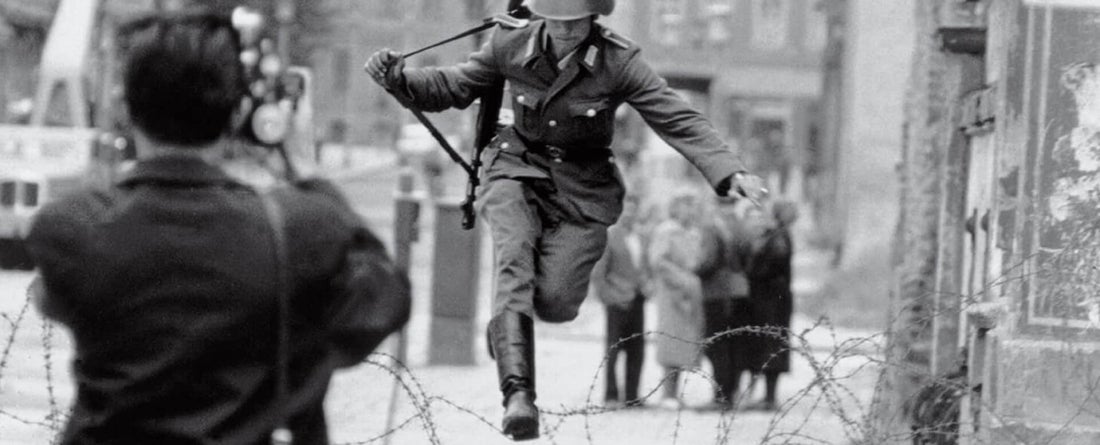 Photograper snapping photo of military man jumping over barbed wire