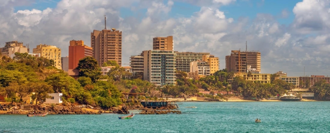 bright turquoise waters sit in front of tall buildings on the coastal skyline of Dakar, West Africa