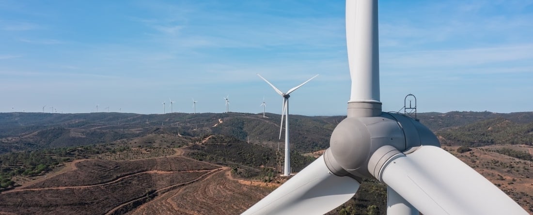 A wide view of mountains in Portugal during the day, with winds turbines extending into the background