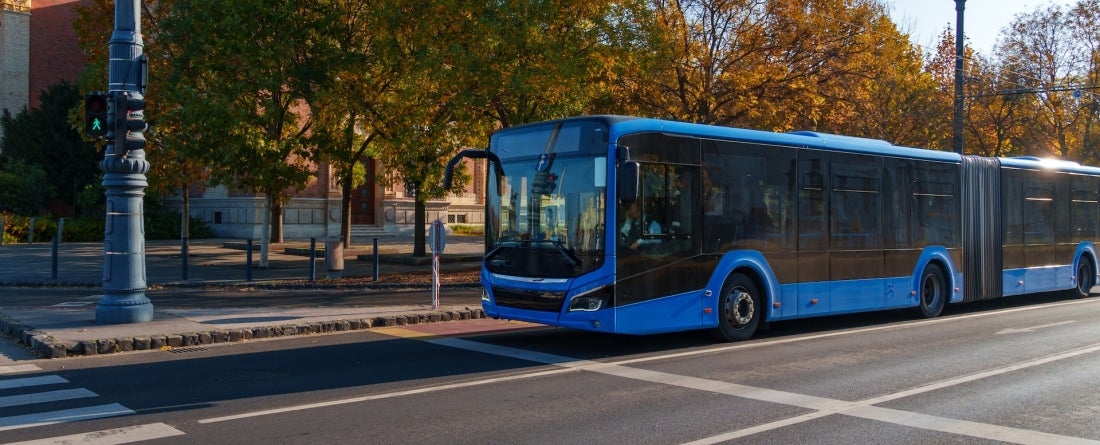 A city bus waiting at a suburban intersection 