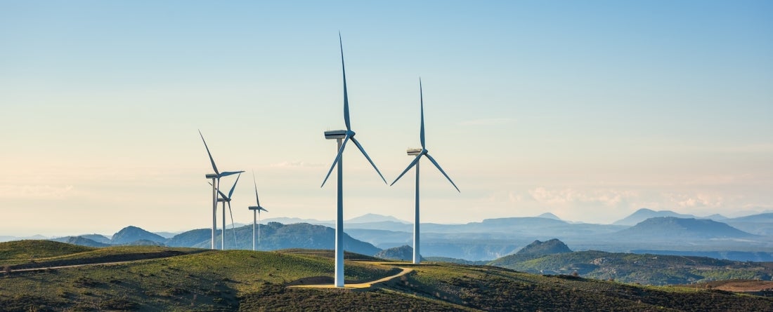wind turbines in an open field at sunset