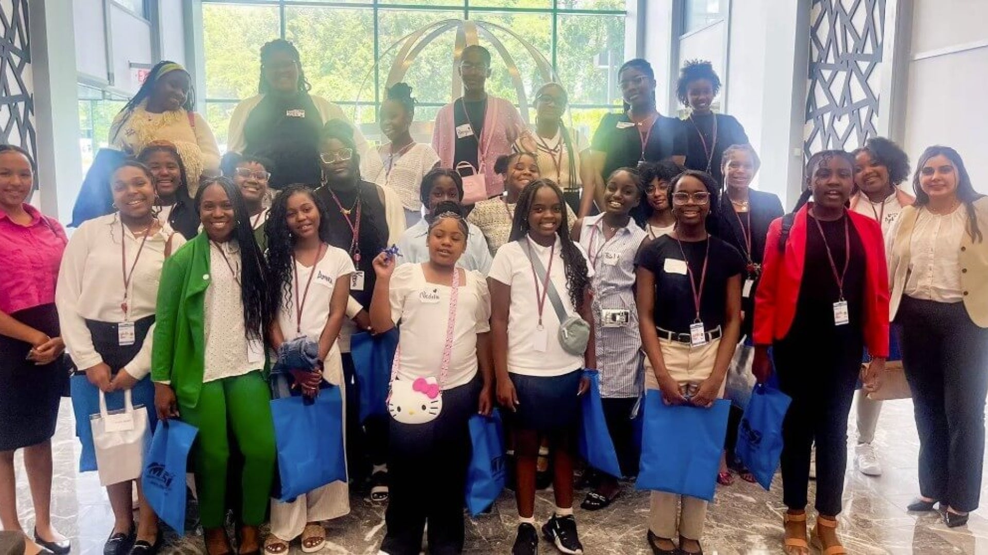 group of women and girls standing together holding blue bags and wearing name tags